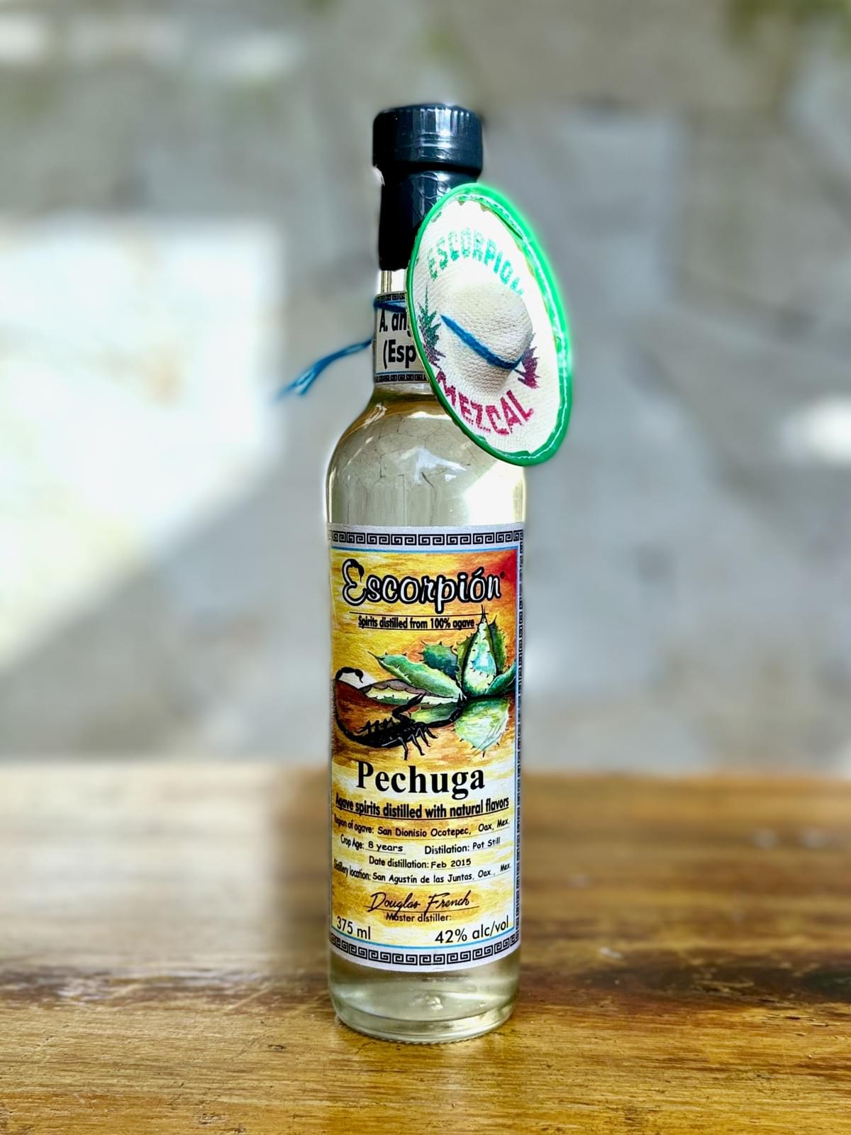 Bottle of Escorpion Pechuga mezcal on a rustic wooden table. 
