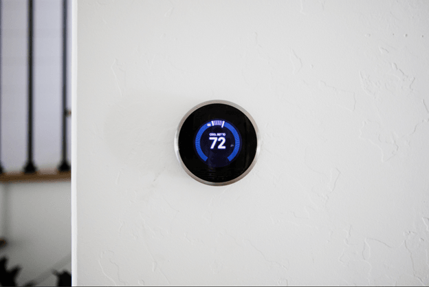 Round digital thermostat reading 72 degrees on a white wall.