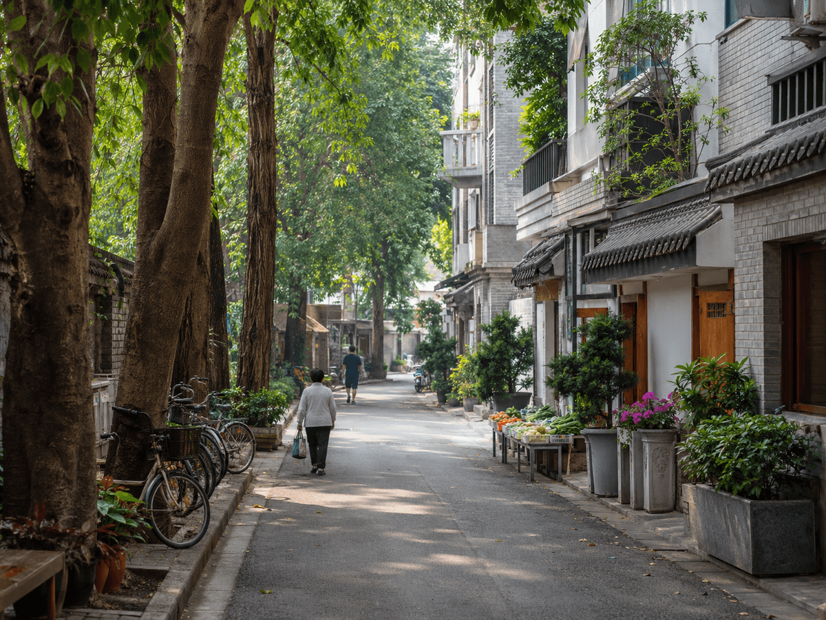 Quiet tree-lined Chengdu neighborhood with bicycles, local homes, and a produce stall.