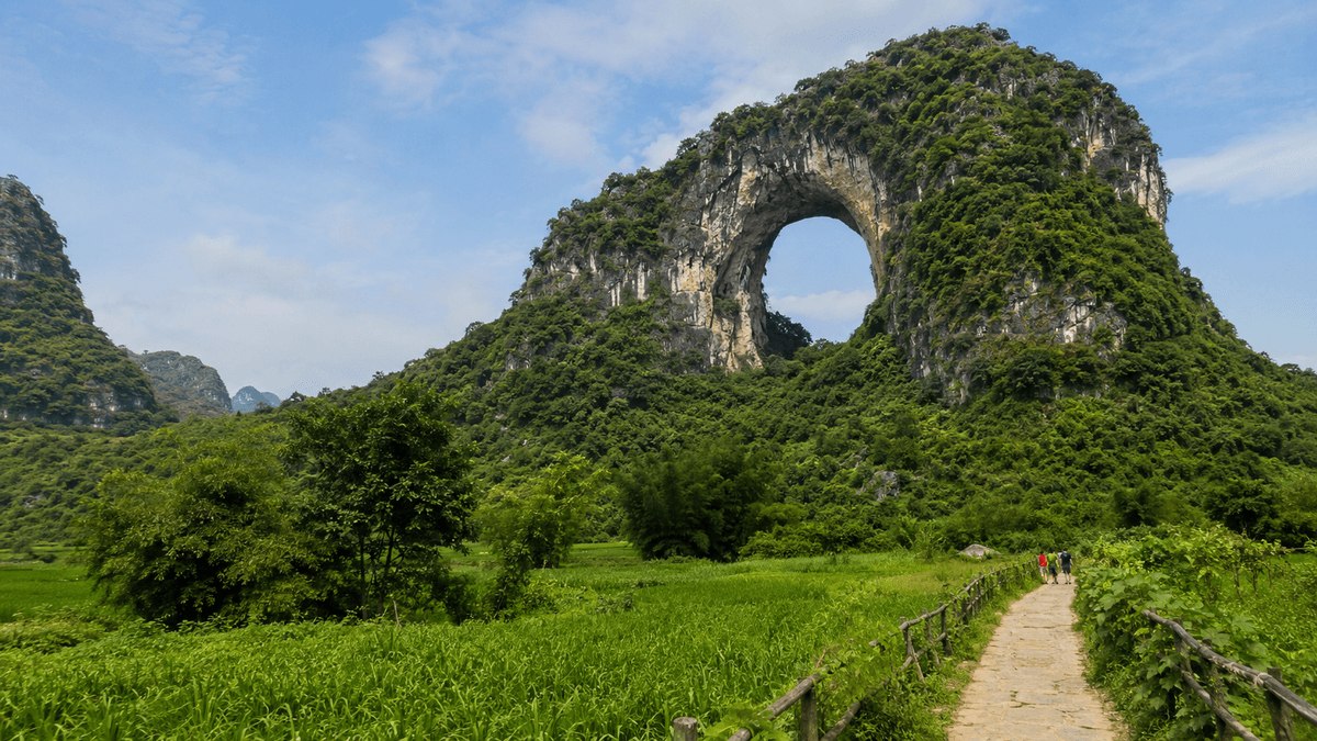 Natural limestone arch at Moon Hill surrounded by green Yangshuo countryside