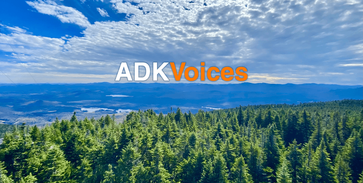 ADK Voices Logo overlaying photo of hikers on top of mountain range with fall orange and yellow trees in the distance.