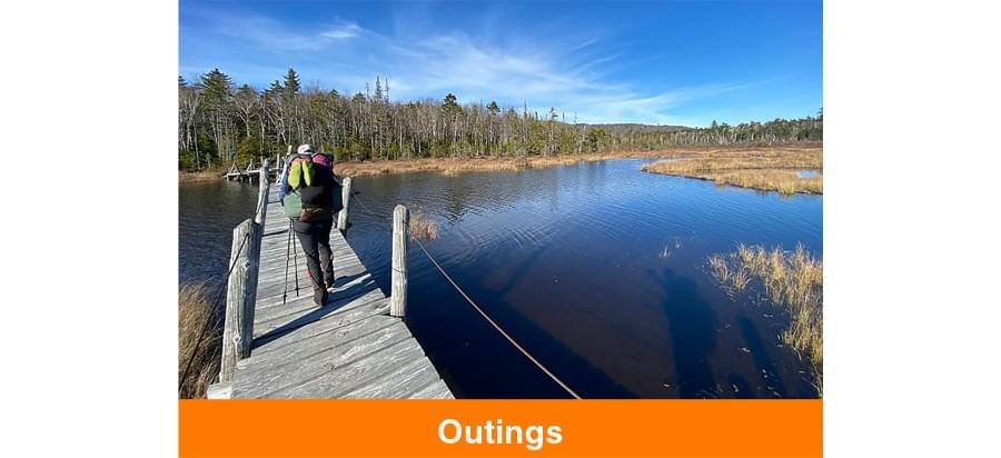 Outings - photo of a hiker on the dock by the water.