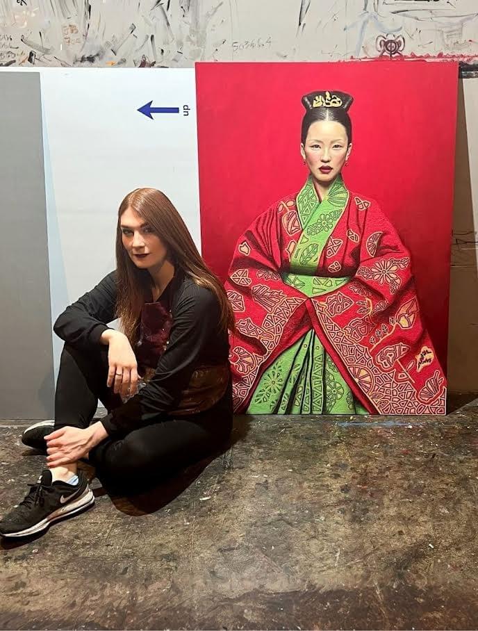 Artist Yael Medrez Pier seated in studio next to large portrait painting