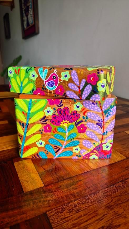 Hand painted decorative box by AMMO featuring colorful birds, flowers, leaves, and nature inspired patterns that showcase her vibrant organic illustration style.