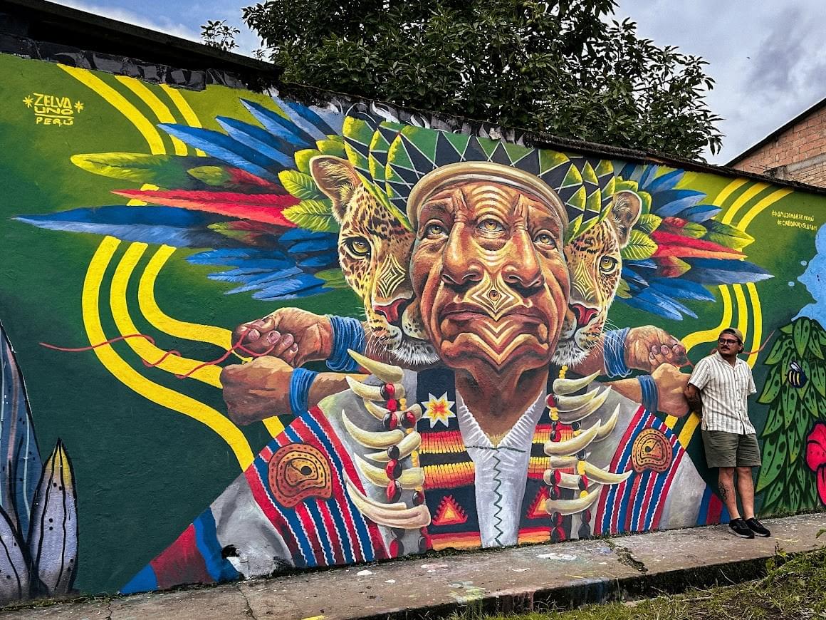 Mural by Zelva Uno of an indigenous elder with jaguars and vibrant Amazonian patterns symbolizing ancestral strength and cultural identity