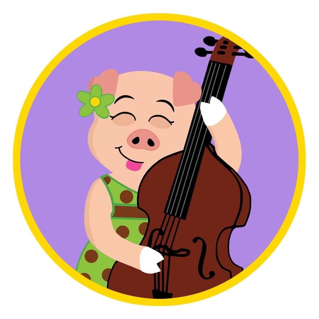 Dotty Pig smiling while playing a bass guitar.