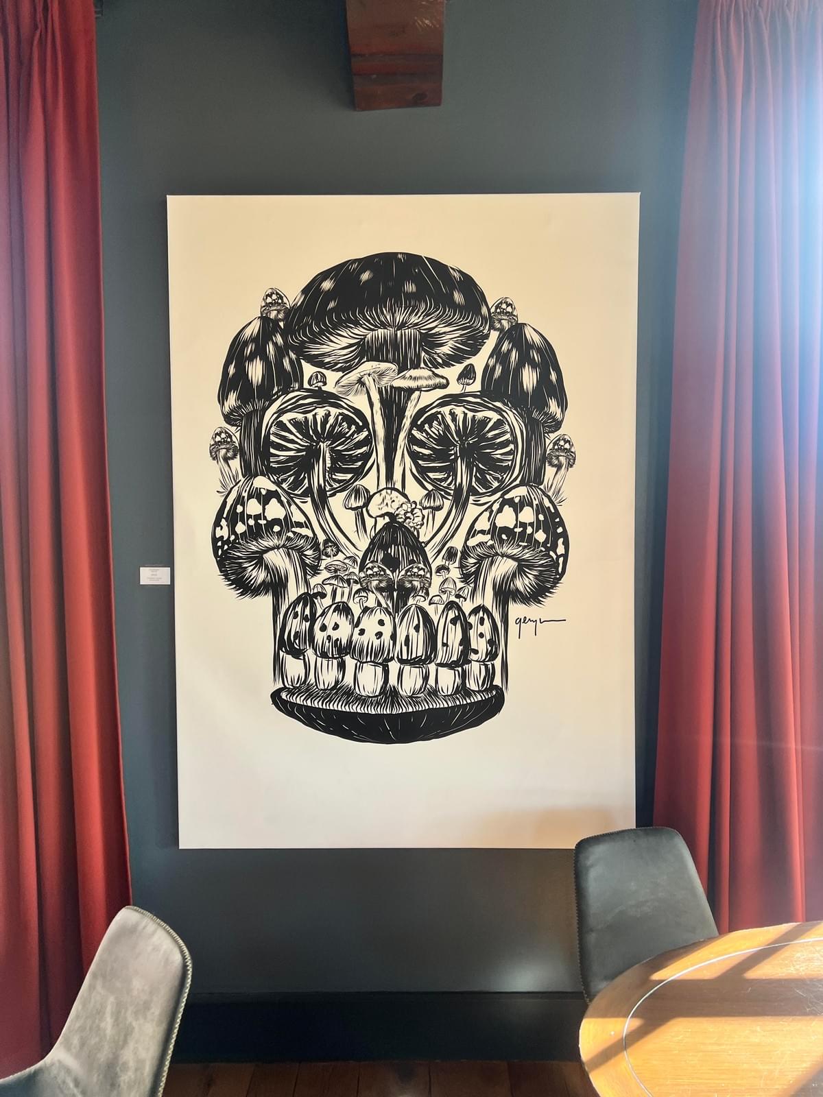Black and white skull artwork by Gennaro Garcia created from detailed mushroom illustrations and organic forms displayed in a modern interior space with dramatic contrast and symbolic design