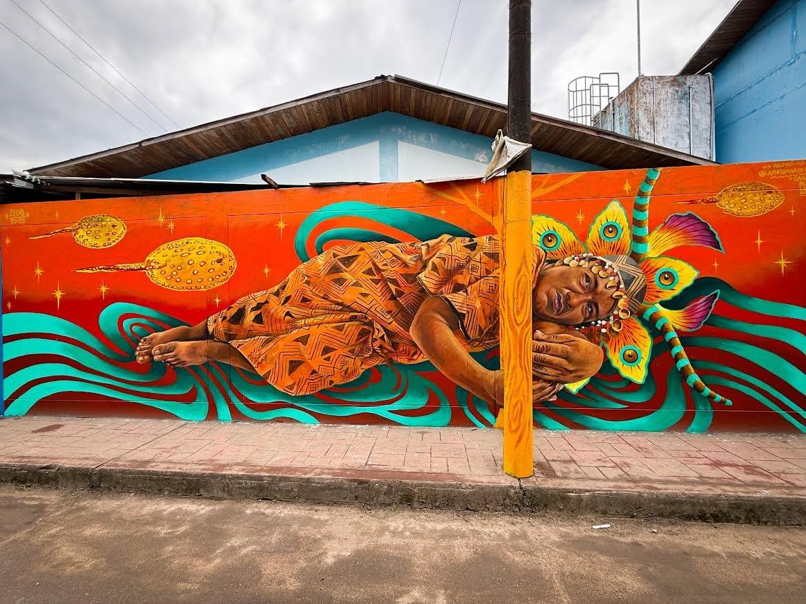 Vibrant mural by Zelva Uno of an Amazonian figure resting with butterfly elements and flowing patterns symbolizing dreams and connection to nature