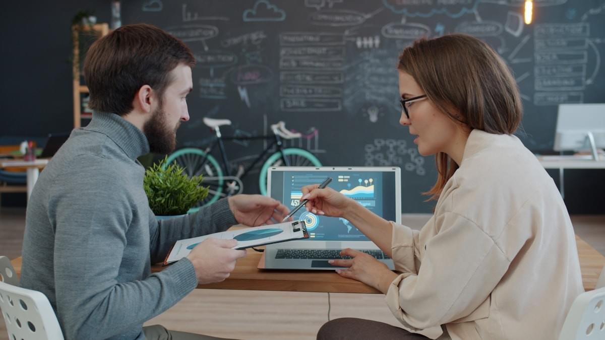 Two colleagues reviewing business performance data together on a laptop