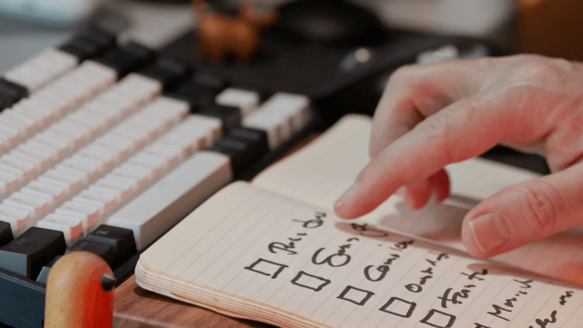 Person checking completed website inspection tasks in a notebook beside a computer