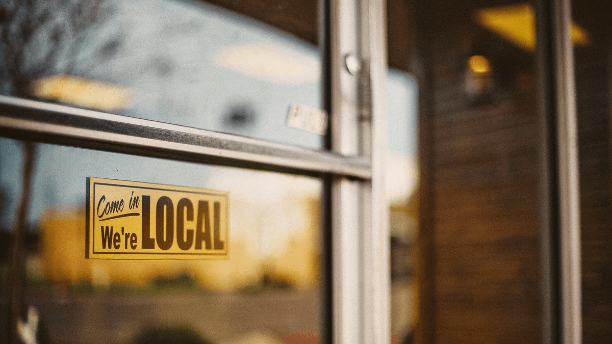 Yellow Come in We're Local sign on a neighborhood storefront