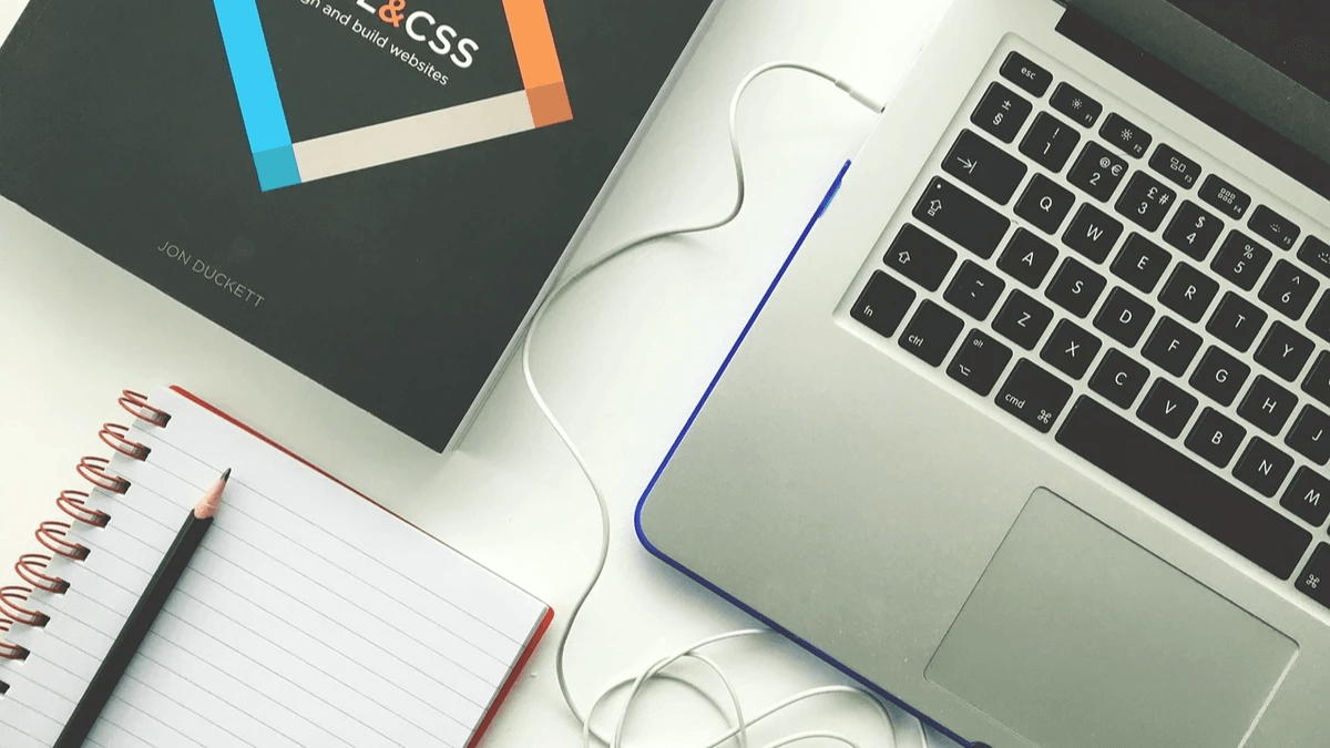  Laptop, notebook, and web design reference arranged for planning a clearer homepage