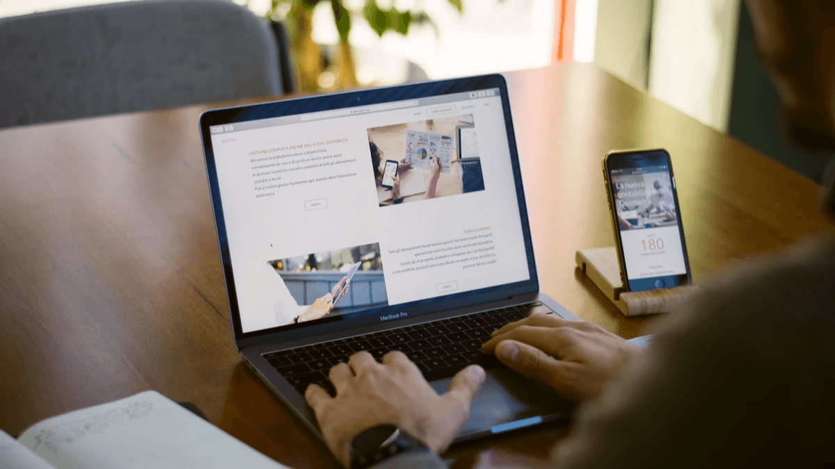 A woman browsing products on a laptop while taking notes