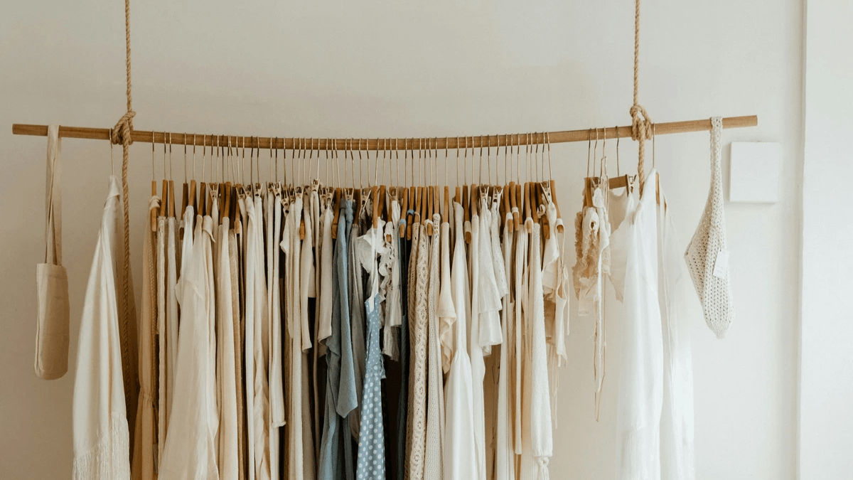 Clothing arranged by type on racks inside a bright boutique