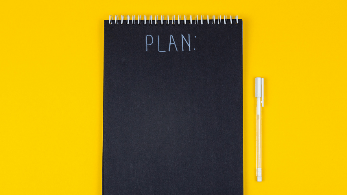 Black Notebook with White Pen on Yellow Background