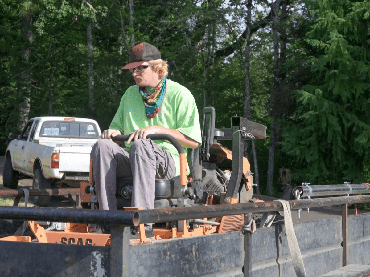 Landscaping employee operating riding lawnmower