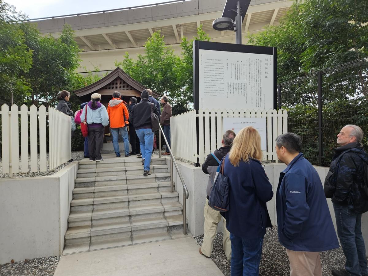 Numerous YCAPS members view a small wooden shrine to the Namamugi incident and the man who died there. The little shrine is tucked up against the Kirin Beer Factory garden with it's lush green trees and under a raised expressway.