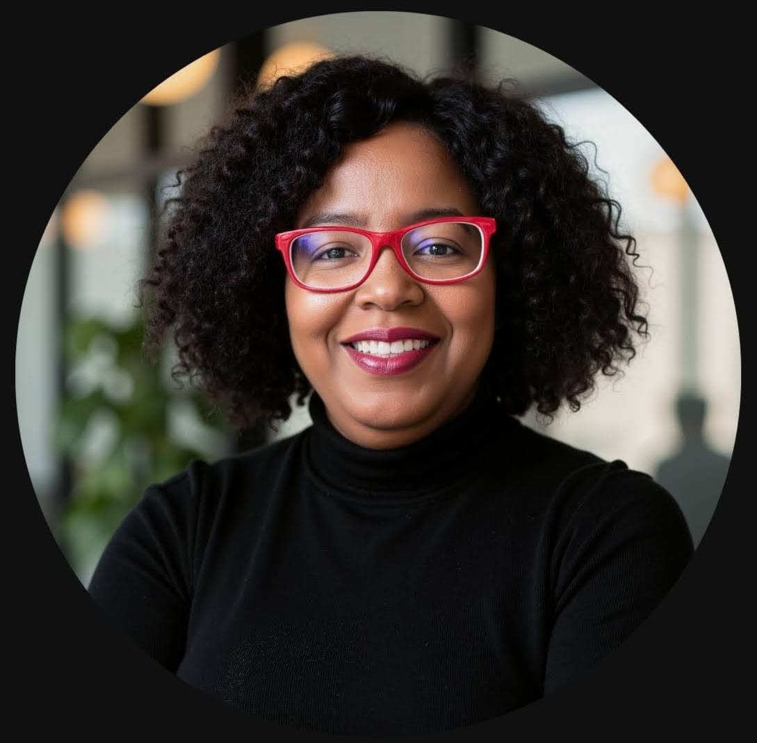 African American woman wearing a gray jacket and red eyeglasses.