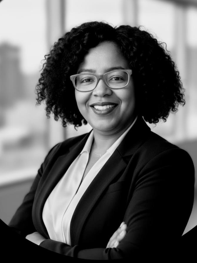 African American woman wearing a gray jacket and red eyeglasses.
