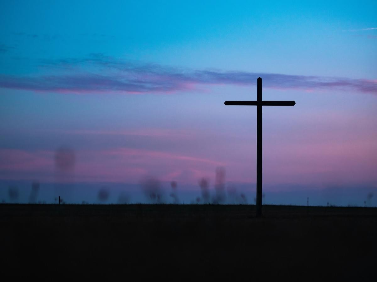 Dark sunset sky with image of an empty wooden cross. 