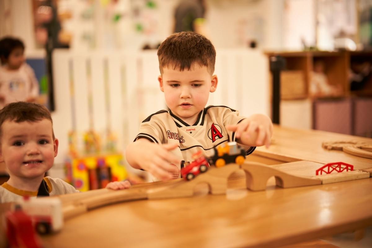 Child exploring with a wooden train set