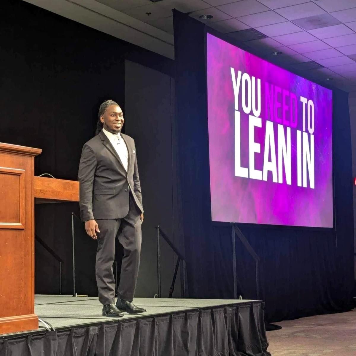 Maurice F. Martin speaking beside a leadership presentation reading You Need to Lean In