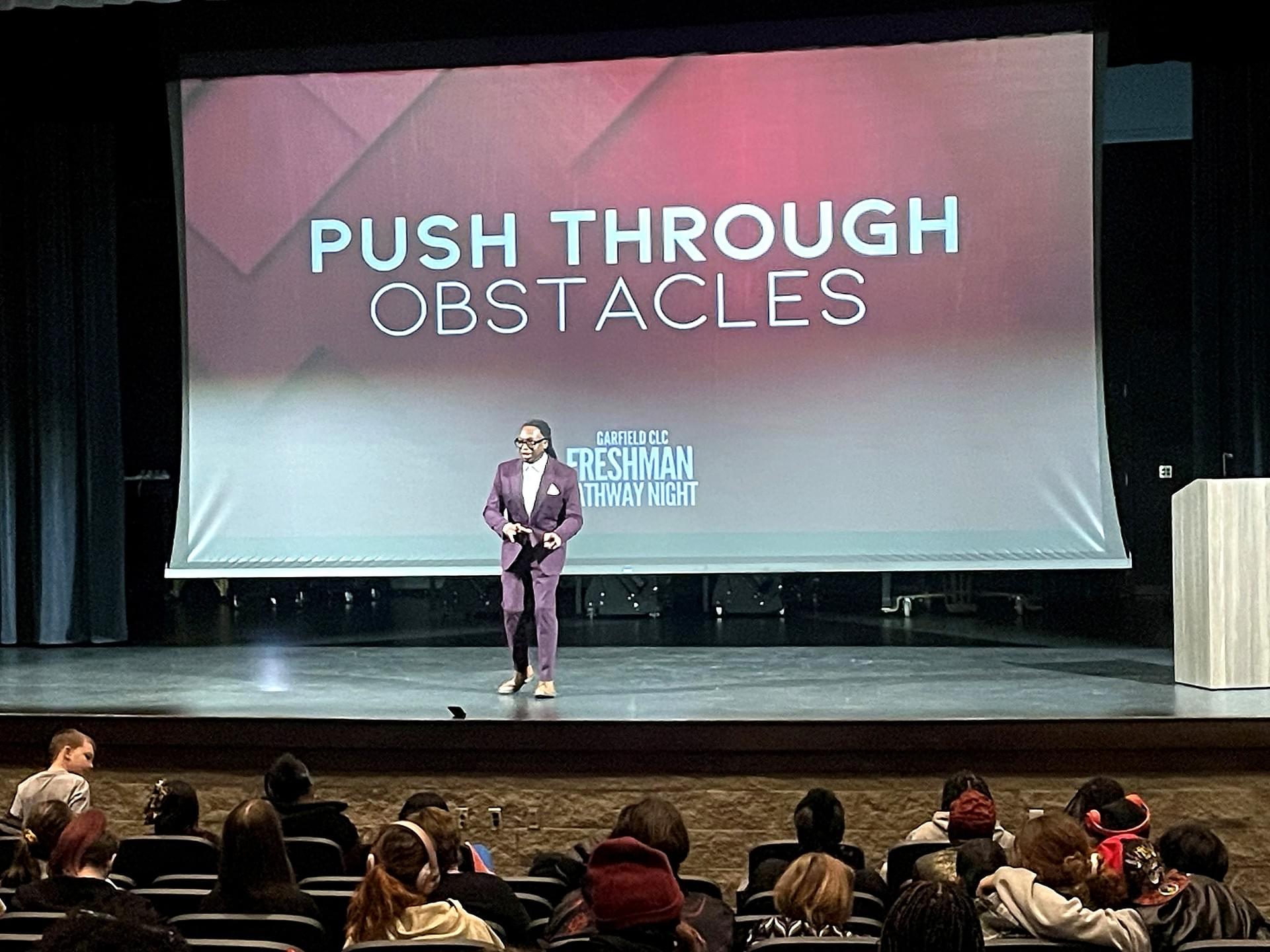 Maurice F. Martin presenting on a college auditorium stage