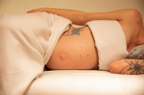 ontblote buik van een zwangere vrouw in zijligging